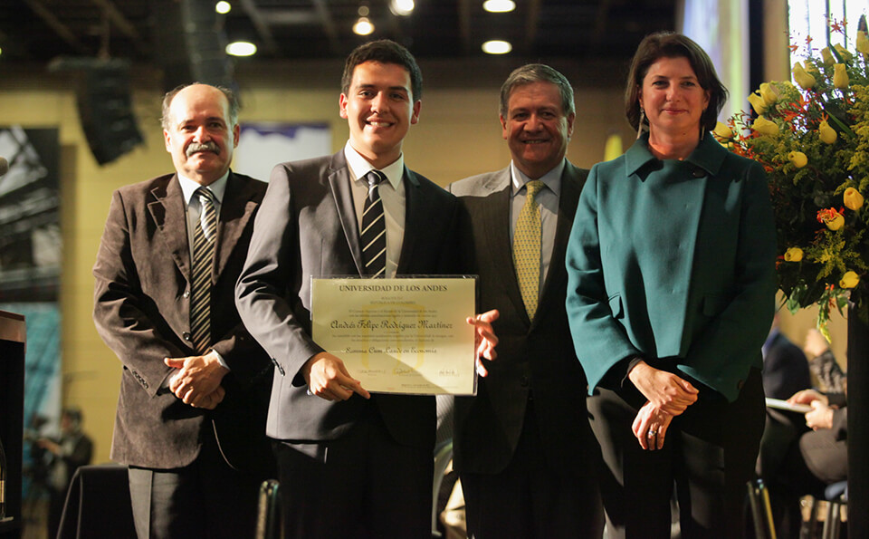 un joven de corbata de rayas muestra su diploma acompañado de dos hombres y una mujer