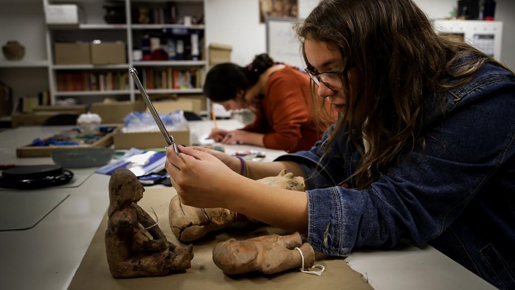 Estudiante manipulando una pieza arqueológica en laboratorio