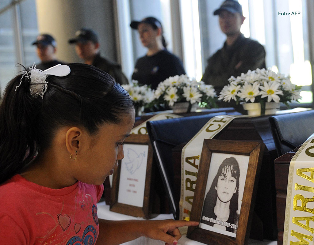 Niña junto a la foto de una mujer desaparecida en la ceremonia de entrega de sus restos.