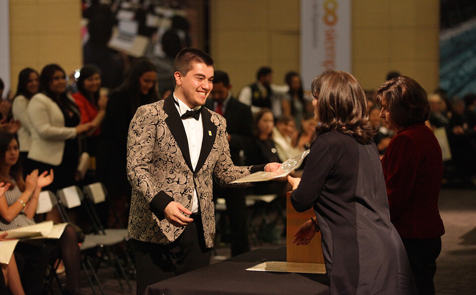 joven con chaqueta de flores y corbatín recibe diploma de grado