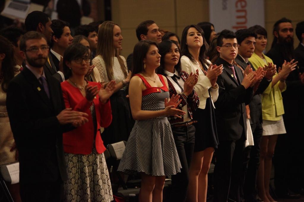 jóvenes en un auditorio aplauden en una ceremonia de grados