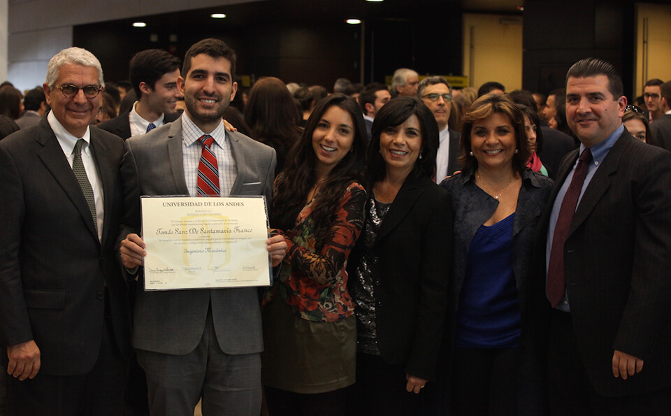 una familia posa para una foto en la celebración de un joven mostrando su diploma
