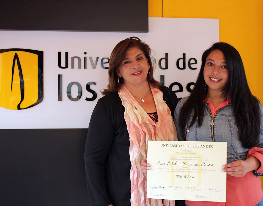 Graduanda y su mamá posan con el diploma de grado para una foto
