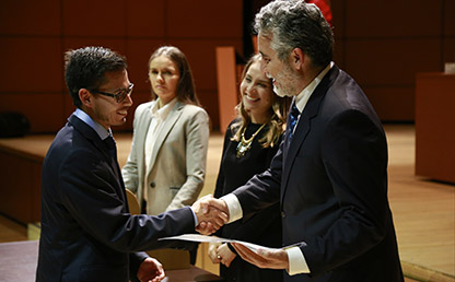 Graduando recibe diploma de manos de Juan Camilo Cárdenas, decano de la Facultad de Economía, en el auditorio Mario Laserna