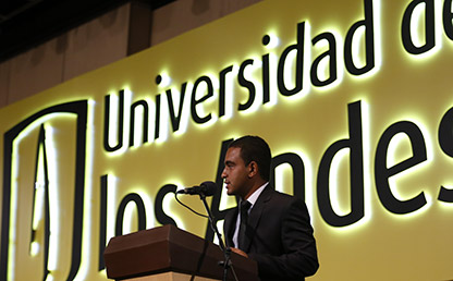 Fabián Vega frente a atril Uniandes dando discurso de grado