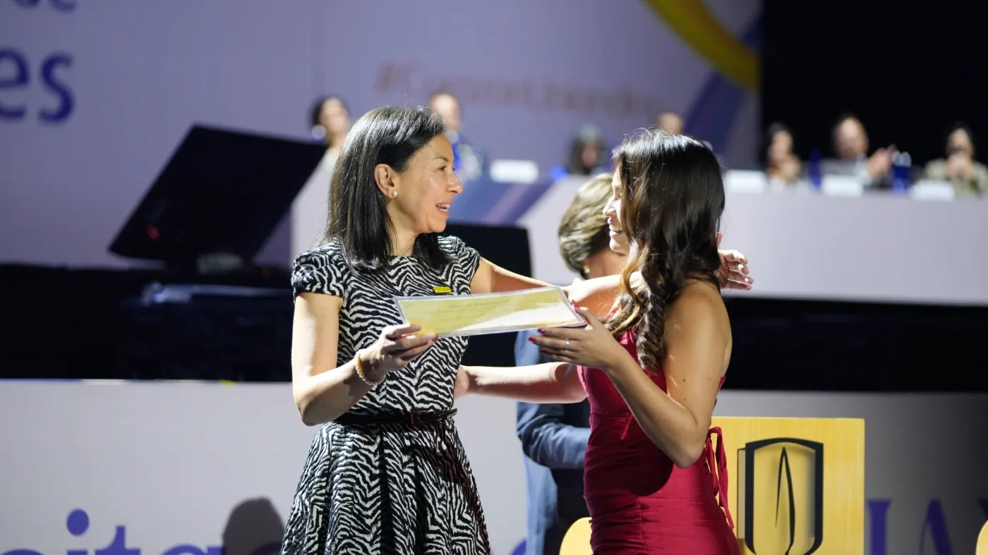 La rectora, Raquel Bernal, le entrega el reconocimiento de responsabilidad social a Lina.