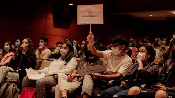 Persona levantando un letrero en medio de una audiencia.