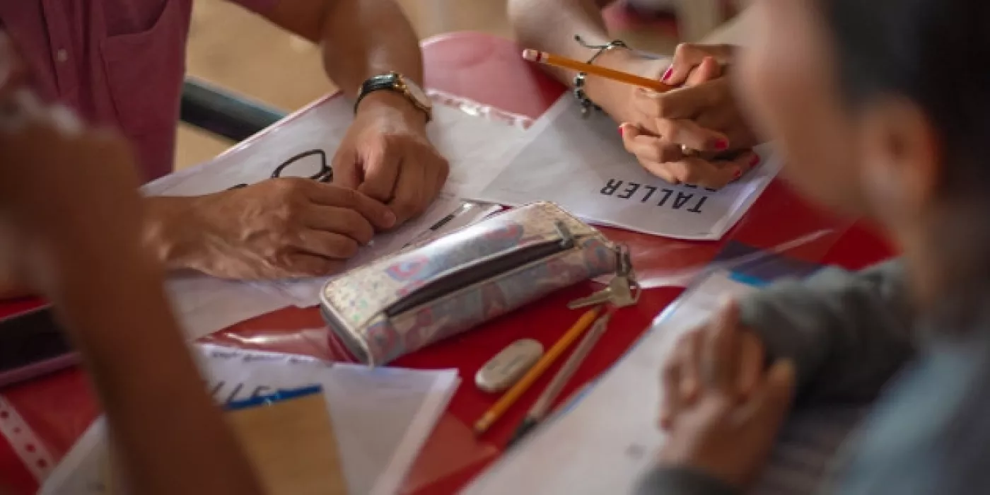 Personas trabajando en una mesa con hojas y utiles