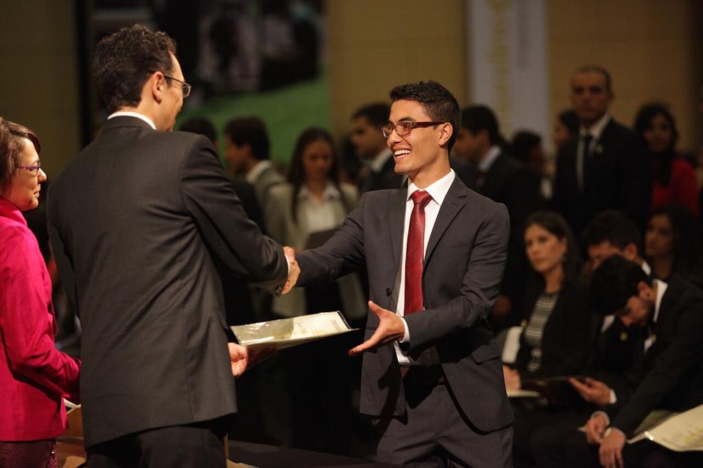 joven de corbata vinotinto recibe diploma de dos personas